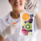 Hand holding an IV drip bag filled with fresh fruit — orange, kiwi, blueberries, grapes